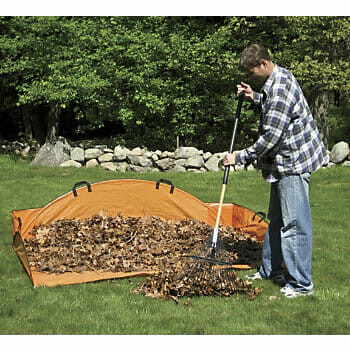 A man in a plaid shirt raking leaves into an orange EZ Leaf Hauler.