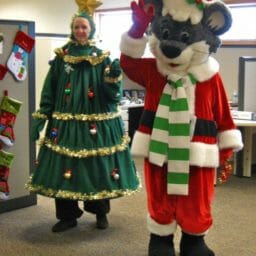 Two people dressed as Chris Mouse and a Christmas tree walking through an office.