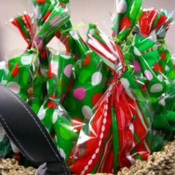 A woven basket filled with small Christmas gift bags.