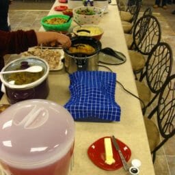A long office kitchen counter set with several food dishes for a buffet.