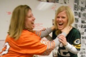 Two blonde women in NFL jerseys, in a playful rivalry of teams.