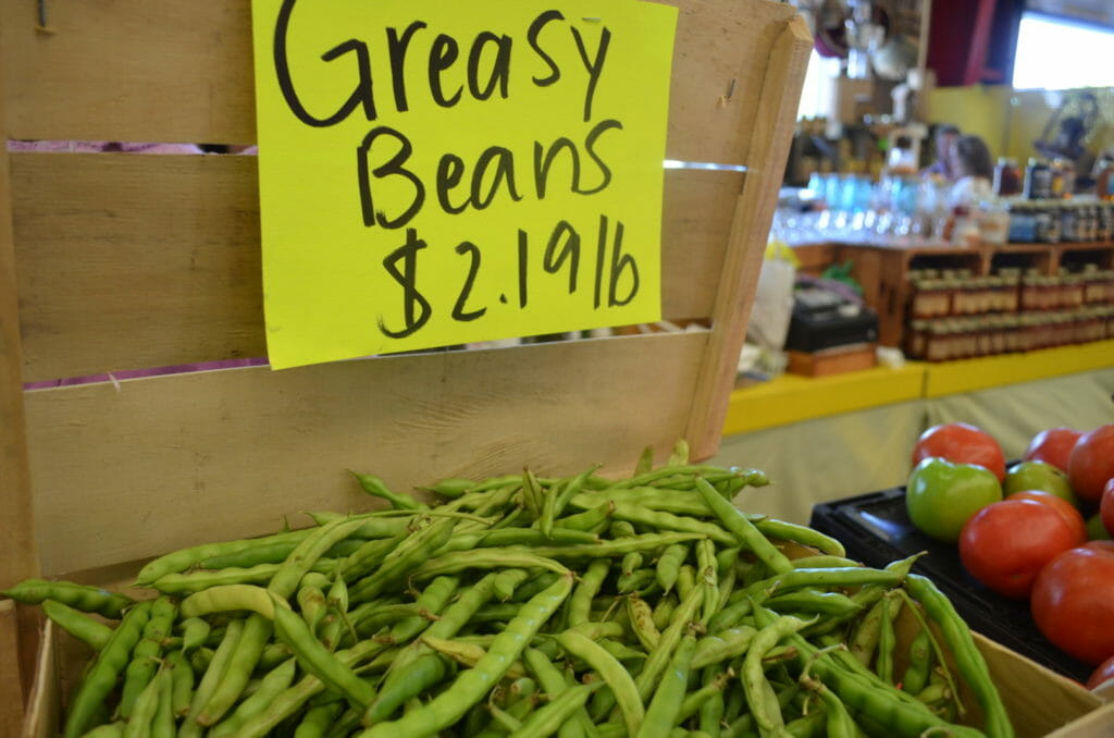 A bin of heirloom beans at a Farmers' Market, with a hand-written sign saying Greasy Beans $2.19 lb.