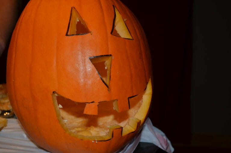 A Jack-o-Lantern face carved into an orange pumpkin.