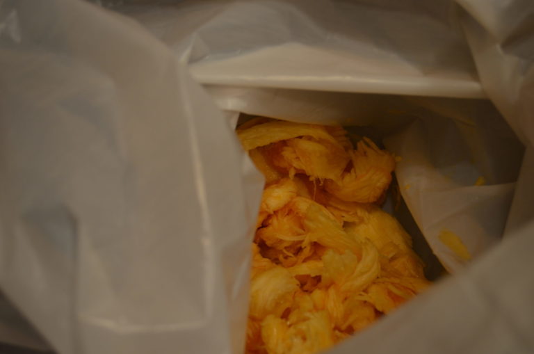 The leavings from a cut pumpkin cavity inside a white plastic bag.