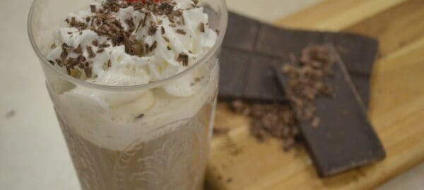 A clear glass filled with Italian Ice Cream Coffee, topped with whipped cream, shaved chocolate and a maraschino cherry.
