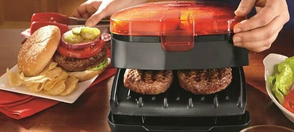 An electric grill with burgers inside, and a plate with a Chipotle Turkey Burger on a bun with chips.