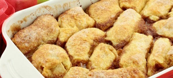 A white and red baking dish filled with Mountain Dew Apple Dumplings.