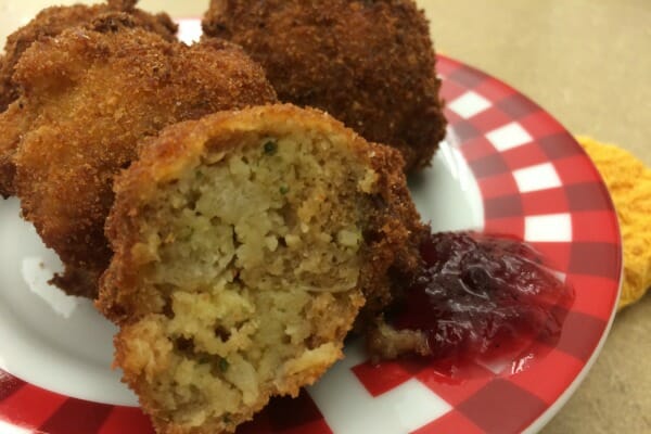 A red and white check plate with three Stuffing Balls, with a side of cranberry sauce.