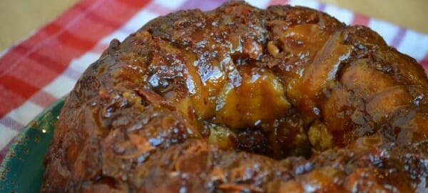 Glazed monkey bread on a green plate, resting on a red and white checkered cloth.