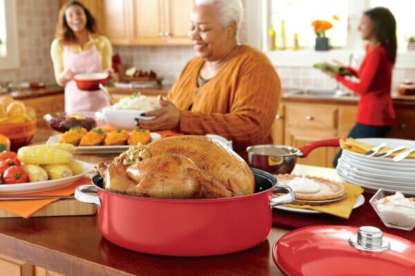 Three black women in a kitchen, with a counter filled with roast turkey, potatoes, pumpkin pie, corn, and more.