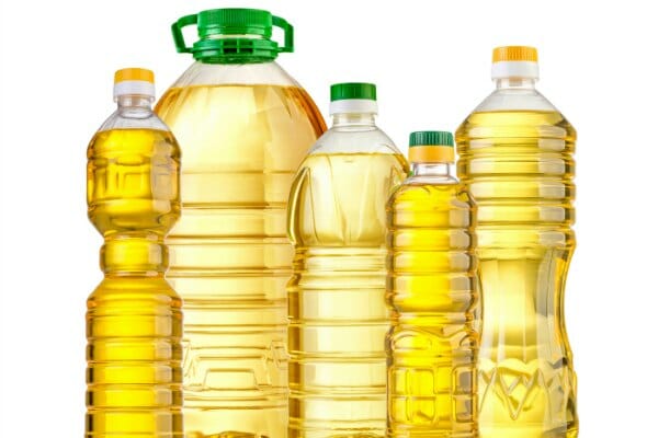 Five bottles of golden cooking oil in different brands and sizes.