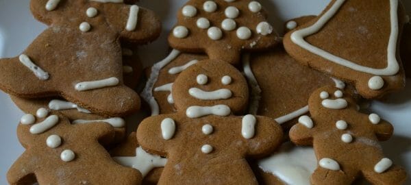 A white and red platter filled with decorated Gingerbread men, bells, and trees.