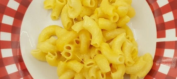 A red and white plate with a serving of golden Microwave Macaroni and Cheese.