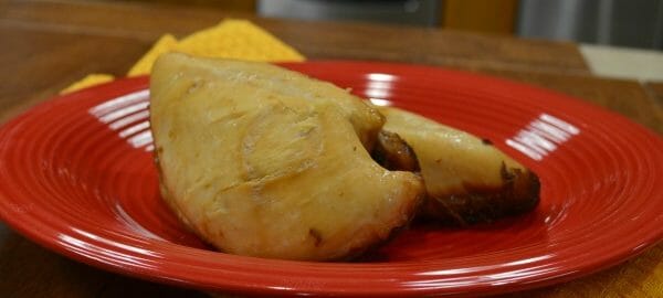 A red plate on a gold placemat with a serving of Sweet Ginger Chicken.