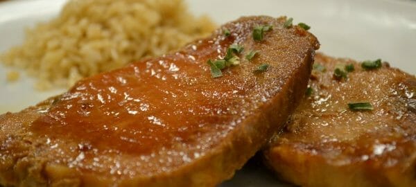 A white plate with a serving of sweet and sour pork chops and rice.