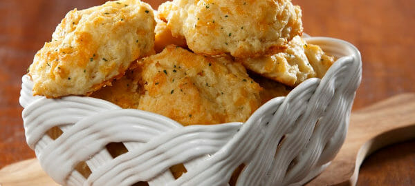 A square white glazed basket filled with golden Garlic Cheese Biscuits.