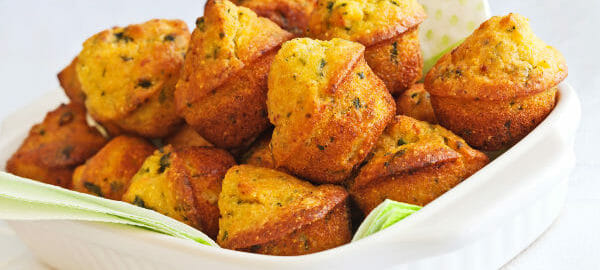 A square white baking dish filled with Cornbread muffins made with chopped chili peppers, bacon, and dried tomatoes.