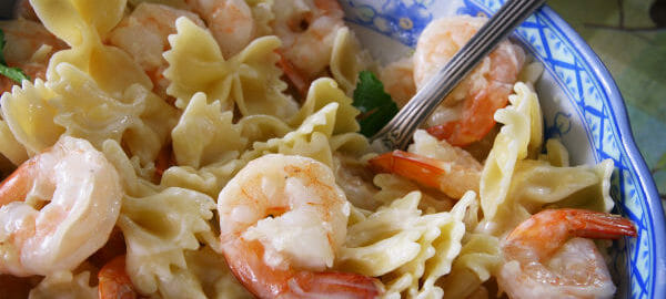 A blue and white floral bowl filled with Shrimp and Bow Tie Salad with a sour cream dressing.