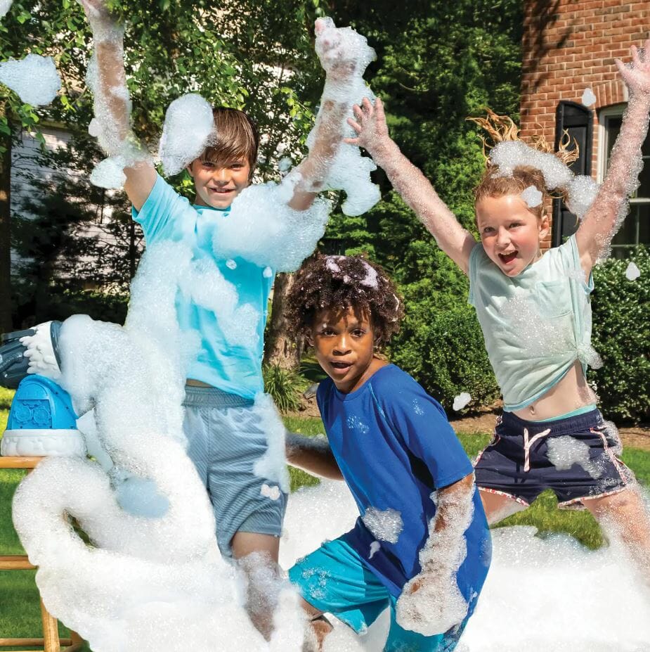 Three children joyfully play in a sea of bubbles, laughing and posing amidst a sunny backyard setting.