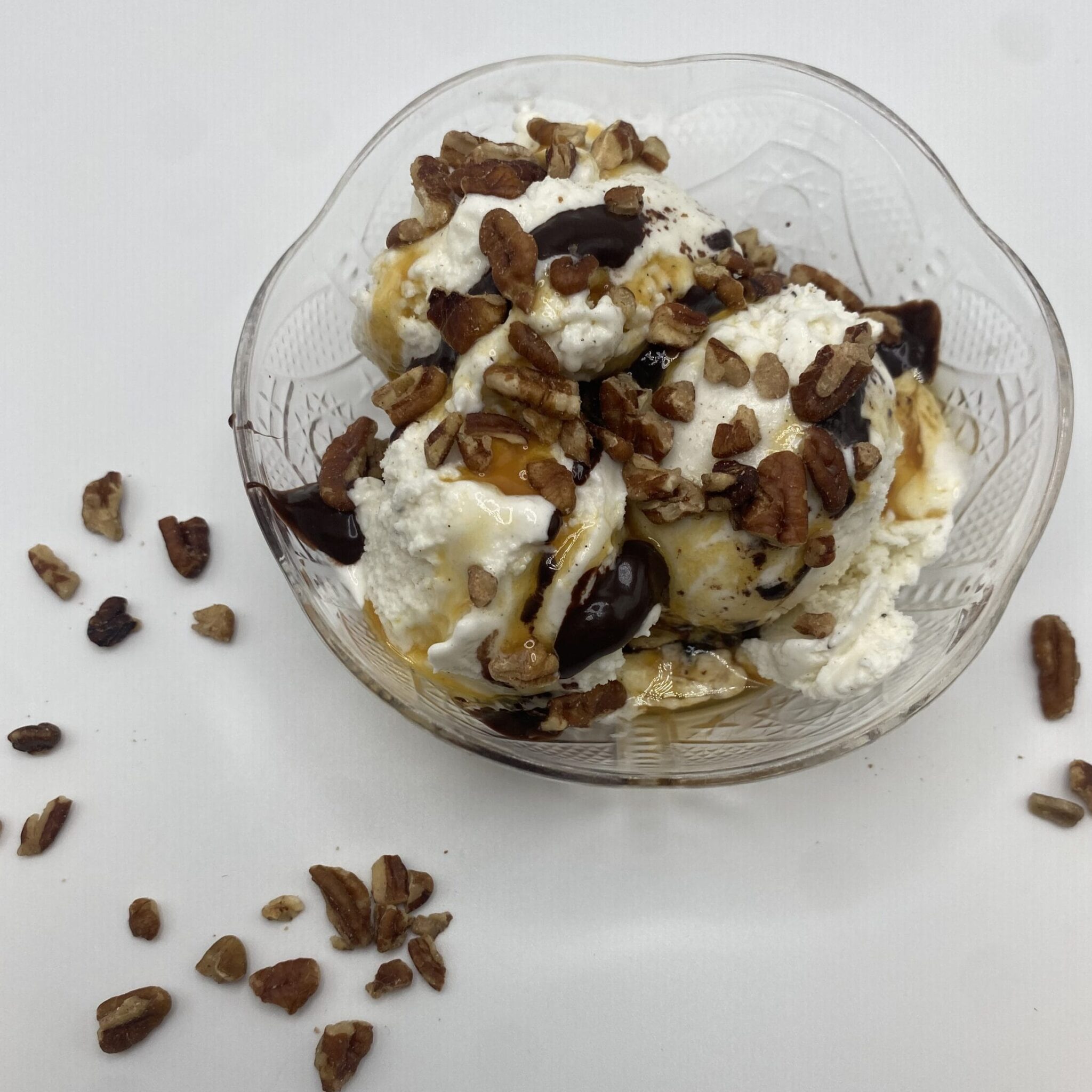 Ice cream bowl with vanilla ice cream, chopped pecans, chocolate syrup, and caramel syrup