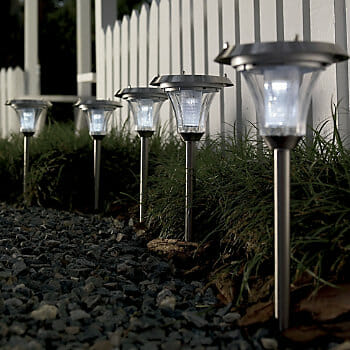 A set of five glowing solar lights along a gravel pathway.