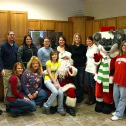 Thirteen people in an office, one dressed as Santa and one dressed as Chris Mouse.