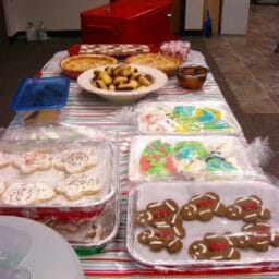Several varieties of Christmas cookies and pies on a long table at an office.