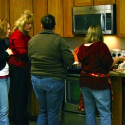 Four people preparing food in an office kitchen.