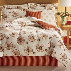 A complete bed set with a reversible comforter in an orange stripe and white with orange and brown circles.
