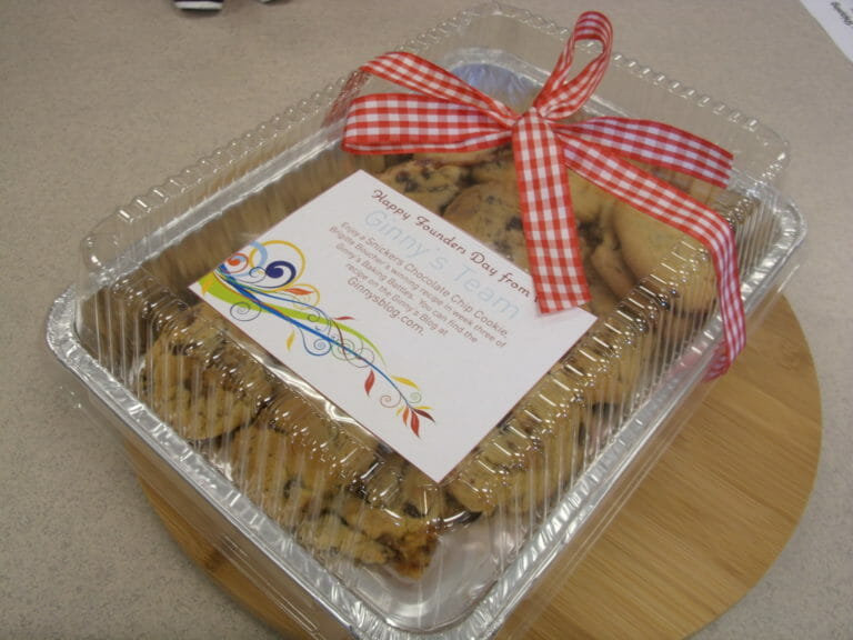 A foiled box of chocolate chip cookies with a red check bow, celebrating Founders Day.