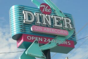 A retro green and pink neon sign for The DINER on Abercorn, Open 24 hours.