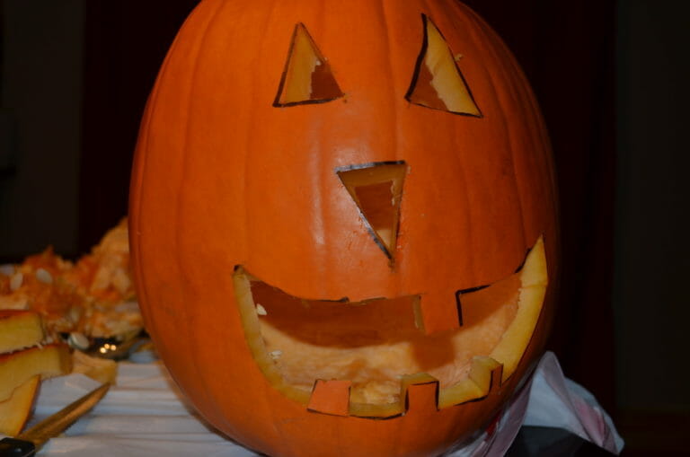 A Jack-o-Lantern face carved into an orange pumpkin.