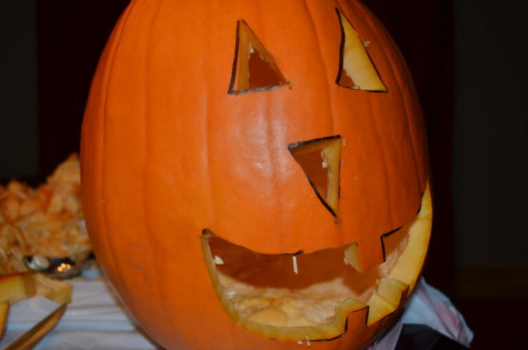 A Jack-o-Lantern face carved into an orange pumpkin.