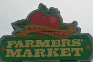A red and yellow sign featuring a red tomato, advertising Nashville Farmers' Market.