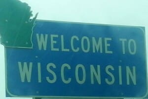 A blue and green highway sign saying Welcome To Wisconsin.