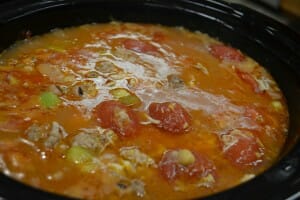 Close-up of a pot of soup with chunks of tomato and different kinds of beans.