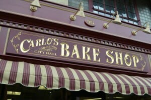 A burgundy and gold awning and sign for Carlo's City Hall Bake Shop, Since 1910.