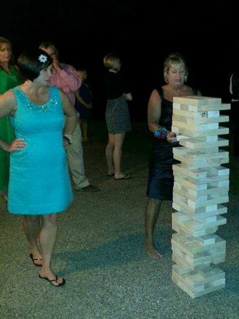 Five people at an event, with one woman pulling a wood block from a stacked Jumbo Jenga game.