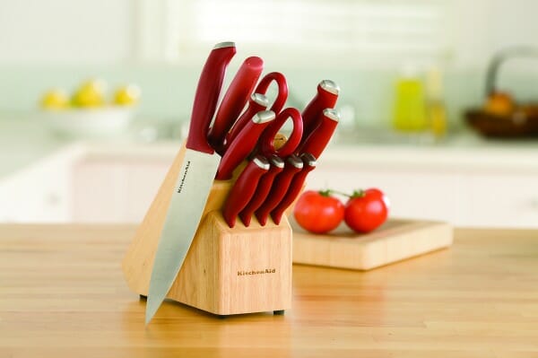 A red-handled KitchenAid knife set in a wood block, placed on a kitchen counter.