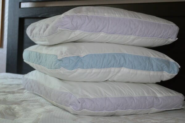 Three stacked bare bed pillows on a bare mattress.