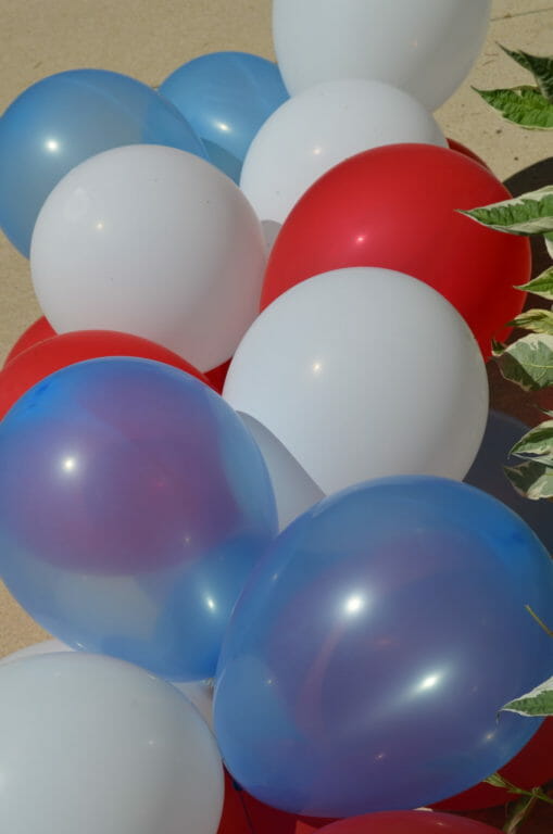 Red, white, and blue balloons strung together on blue embroidery floss through holes on the tied ends.