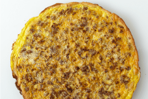 A homemade breakfast pizza of sausage and eggs.