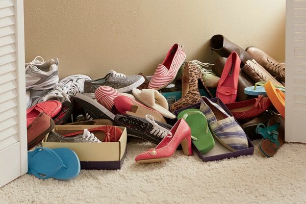 A cluttered pile of shoes on a closet floor.