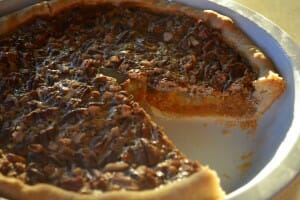 A Pecan Pumpkin Pie in a pie pan, with one slice removed.
