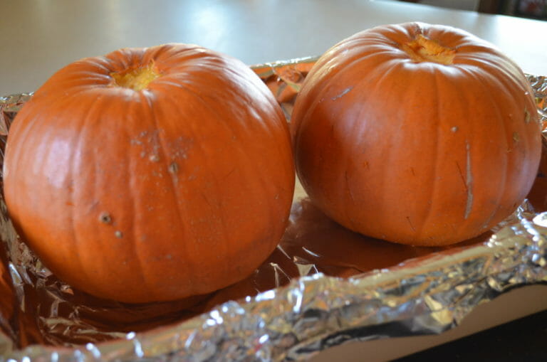 Two small pumpkins in a foil lined pan.