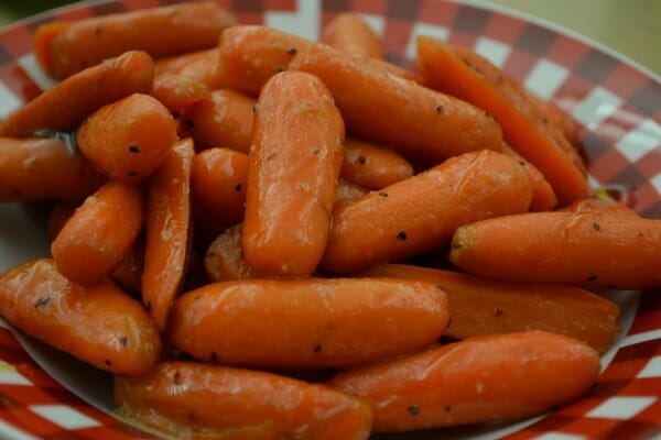 A red and white check bowl filled with Honey Glazed Carrots.