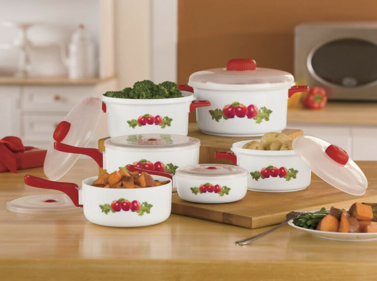 A 12-piece white microwave pan set with red handles and decorated with three red apples.