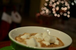Close-up of a green and white mug of hot cocoa with floating mini marshmallows.