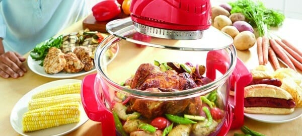 A Ginny's brand air fryer with Roast Chicken and mixed vegetables inside, surrounded by a variety of other foods.