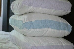Three stacked bare bed pillows on a bare mattress.